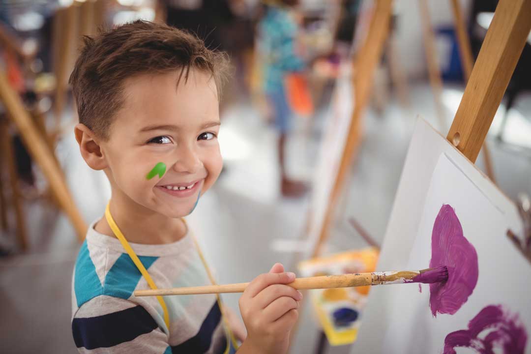 Ein Junge malt in einem miniGenius Kindergarten ein Bild